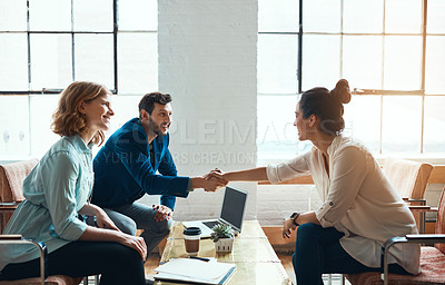 Buy stock photo Shot of a young businessman and businesswoman shaking hands during a meeting in a modern office