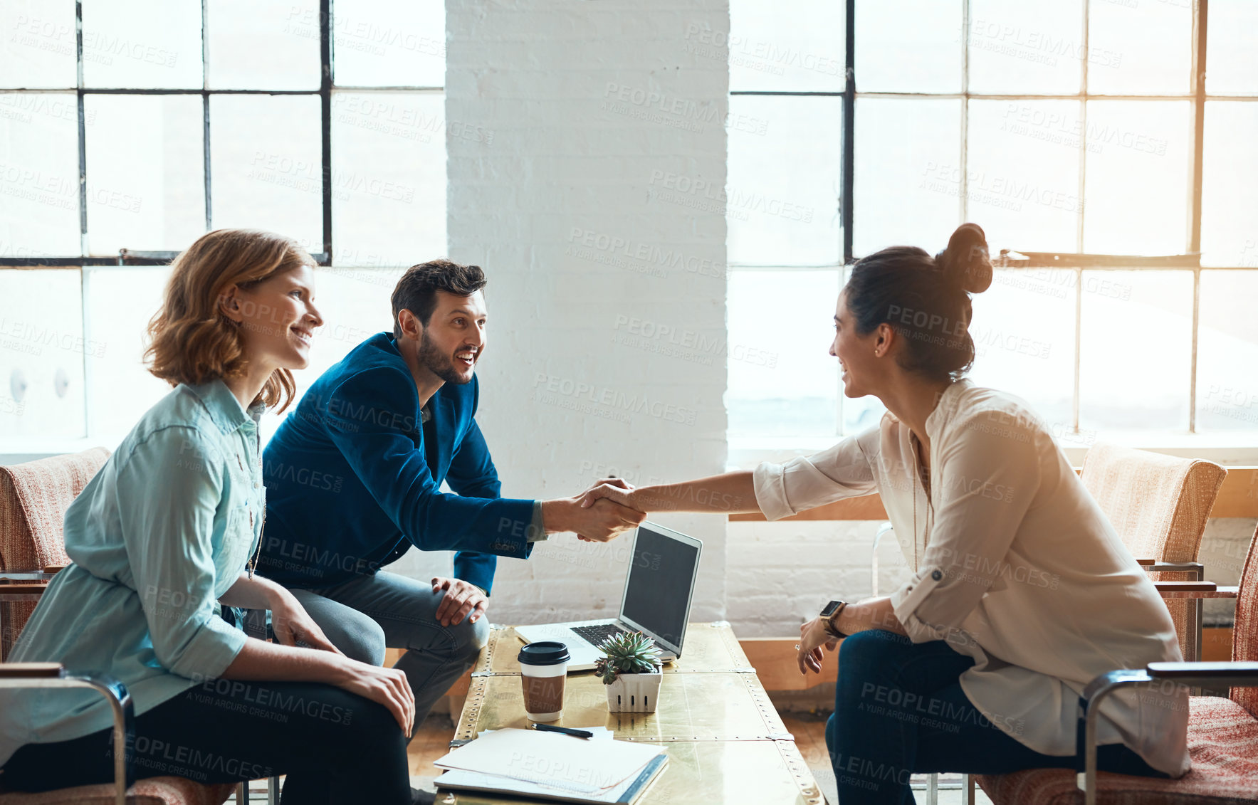 Buy stock photo Shot of a young businessman and businesswoman shaking hands during a meeting in a modern office