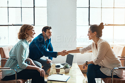 Buy stock photo Shot of a young businessman and businesswoman shaking hands during a meeting in a modern office