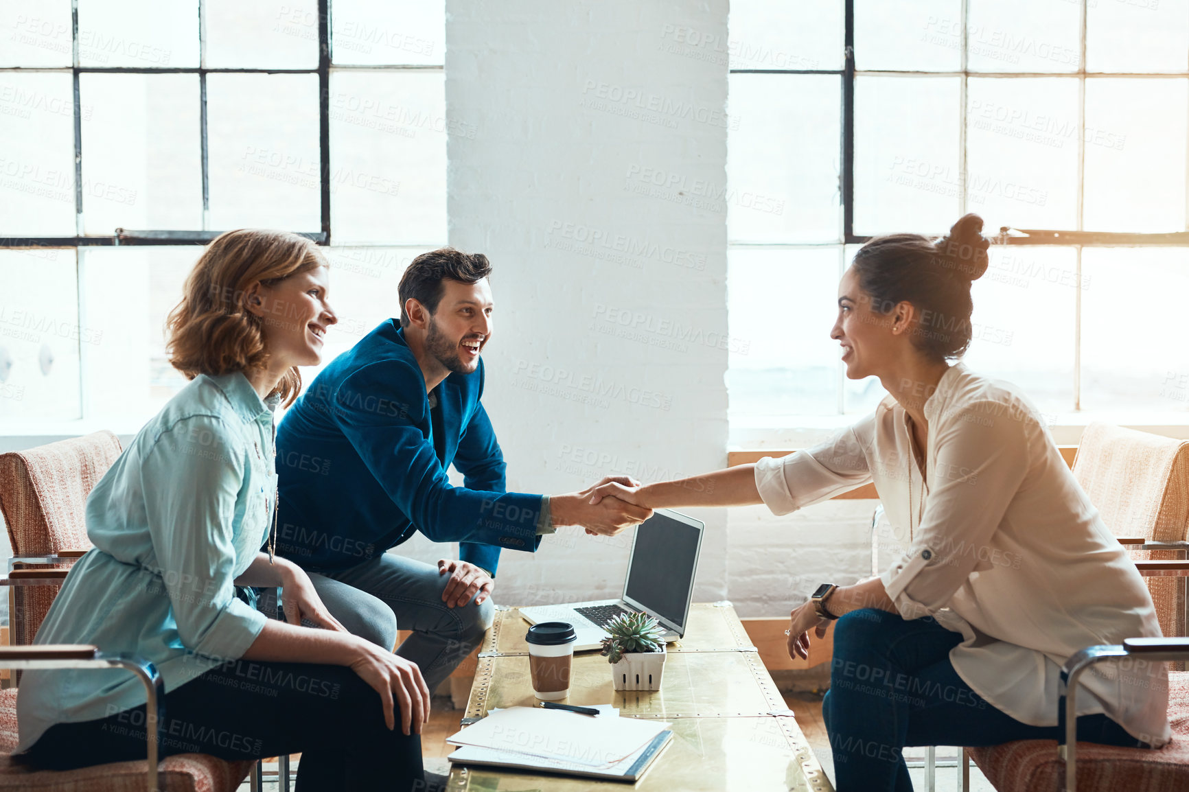 Buy stock photo Shot of a young businessman and businesswoman shaking hands during a meeting in a modern office