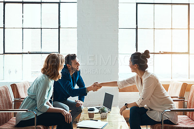 Buy stock photo Shot of a young businessman and businesswoman shaking hands during a meeting in a modern office