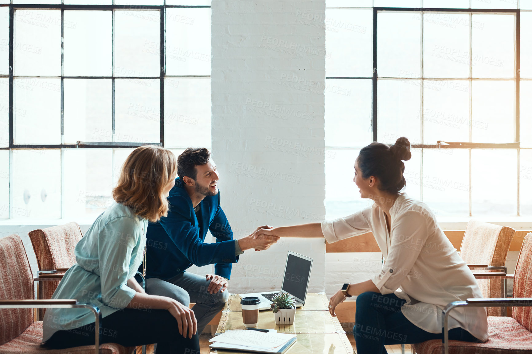 Buy stock photo Shot of a young businessman and businesswoman shaking hands during a meeting in a modern office