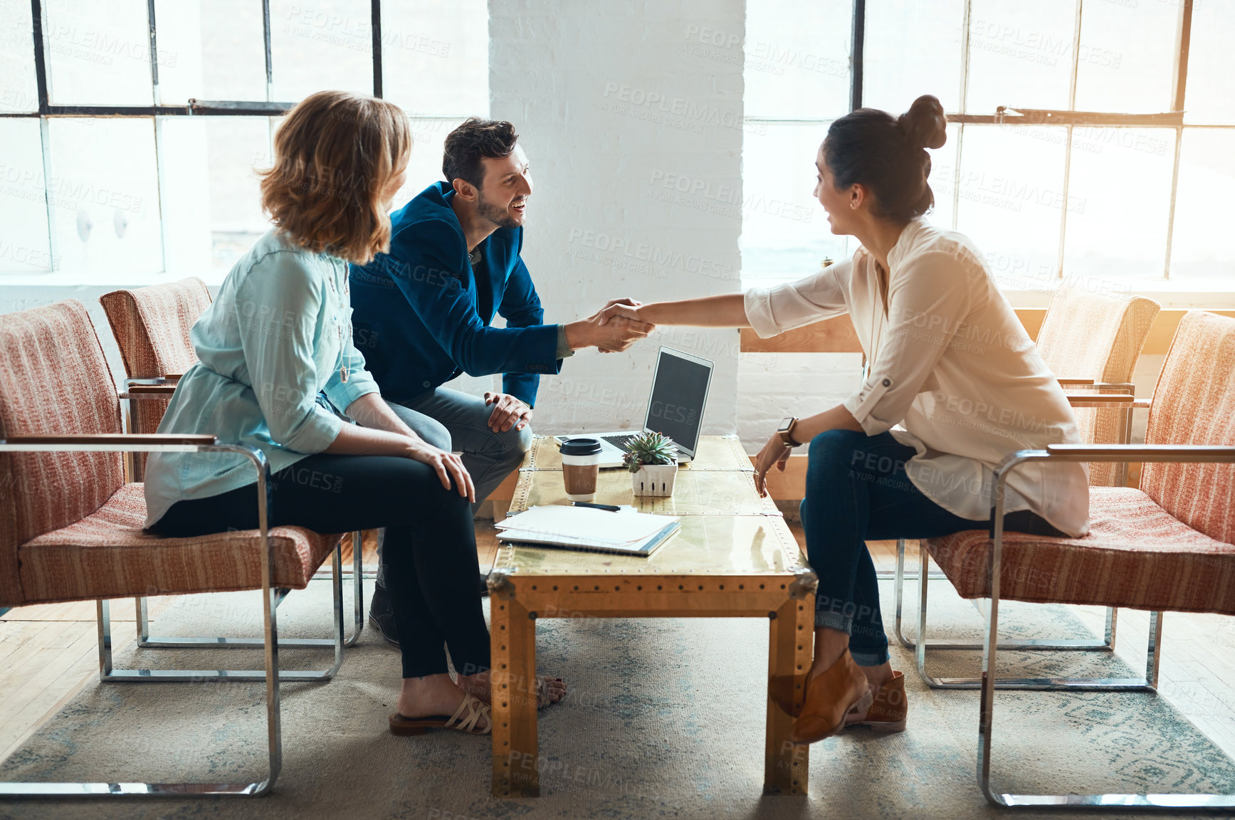 Buy stock photo Shot of a young businessman and businesswoman shaking hands during a meeting in a modern office