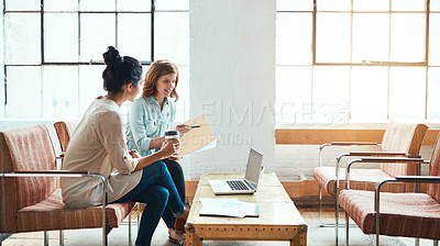 Buy stock photo Shot of two young businesswomen discussing paperwork in a modern office