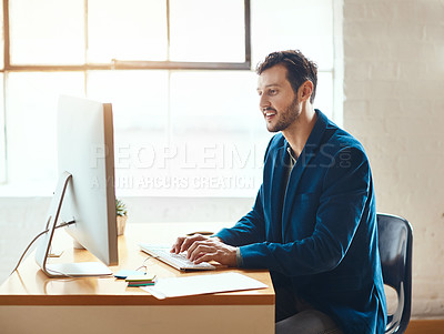 Buy stock photo Cropped shot of a handsome young businessman working on his computer in a modern office