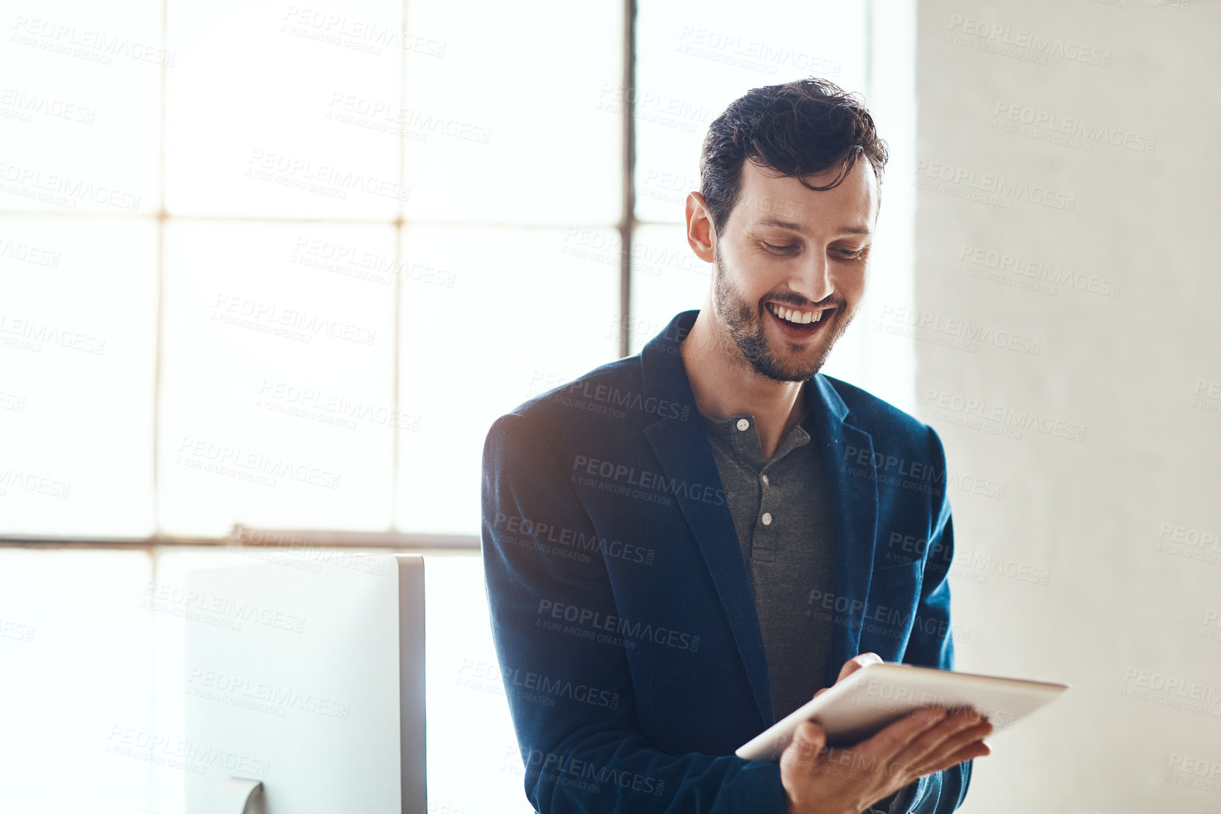 Buy stock photo Cropped shot of a handsome young businessman working on his tablet in a modern office