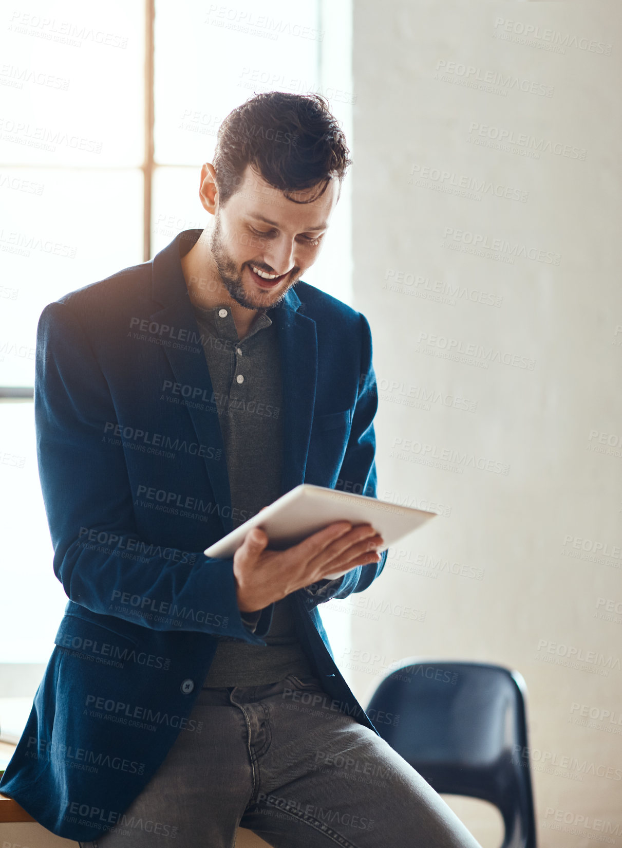 Buy stock photo Cropped shot of a handsome young businessman working on his tablet in a modern office