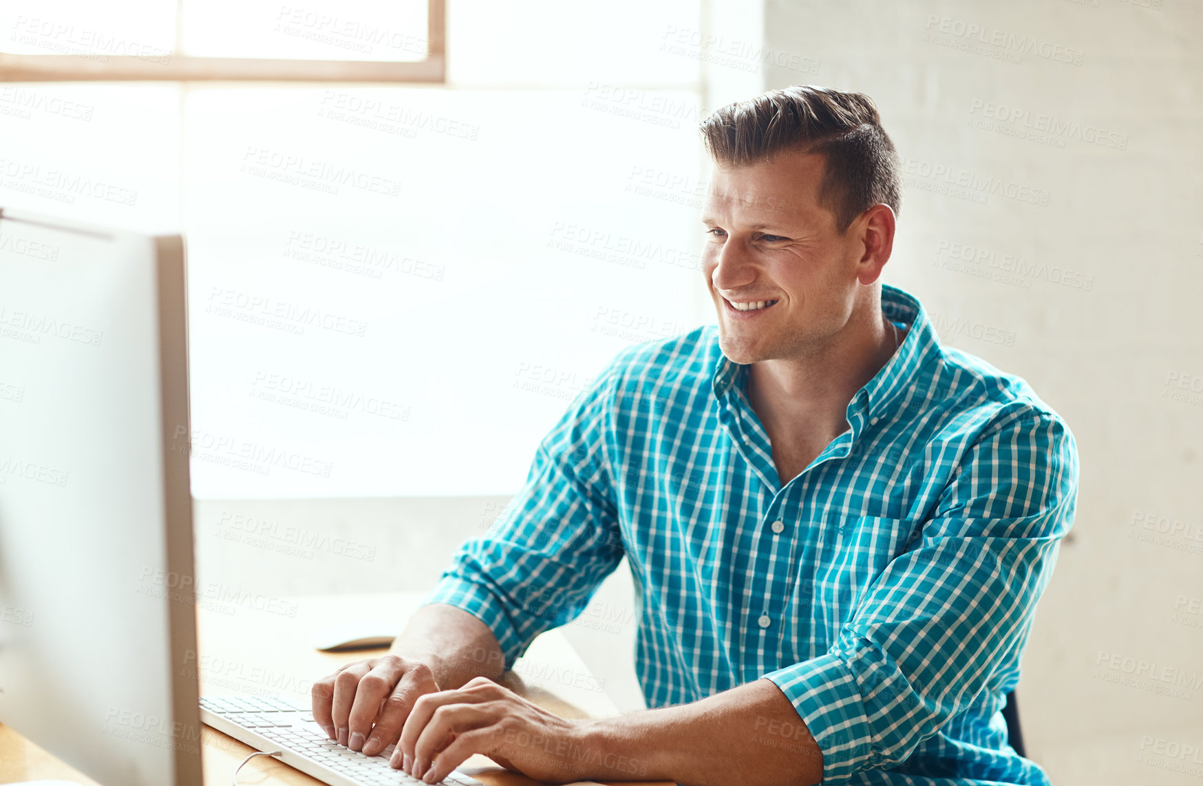 Buy stock photo Cropped shot of a handsome young businessman working on his computer in a modern office