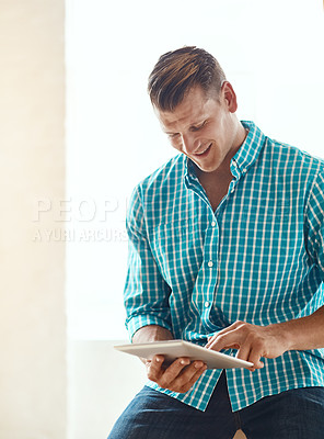 Buy stock photo Cropped shot of a handsome young businessman working on his tablet in a modern office