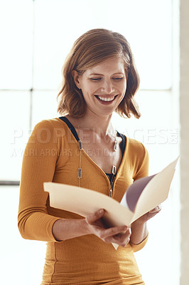 Buy stock photo Cropped shot of an attractive young woman looking over some paperwork in a modern office