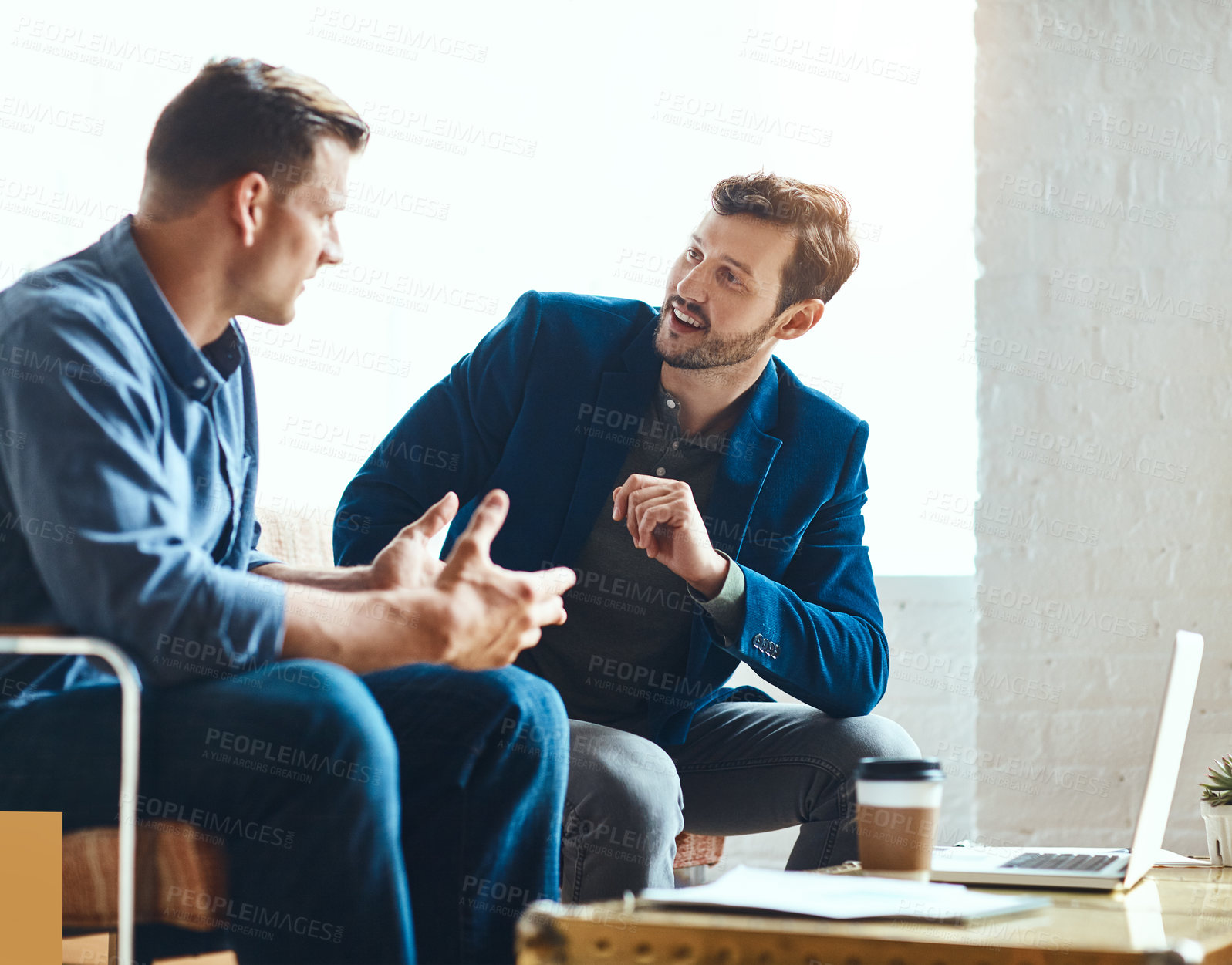 Buy stock photo Cropped shot of two young businessmen working on a laptop together in their modern office