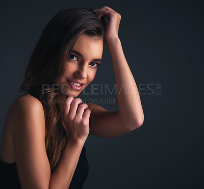 Buy stock photo Studio shot of an attractive young woman posing against a dark background