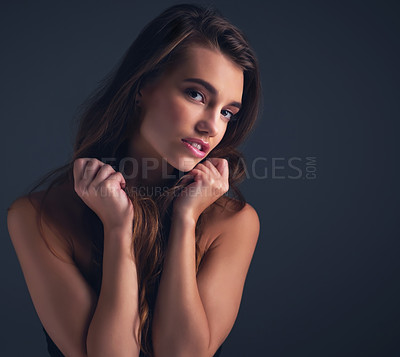 Buy stock photo Studio shot of an attractive young woman posing against a dark background