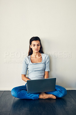 Buy stock photo Shot of a young woman sitting on the floor while using a laptop