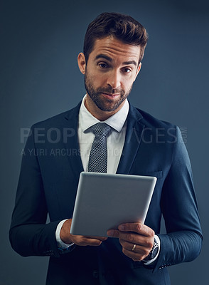Buy stock photo Studio portrait of a handsome young businessman using a digital tablet against a dark background