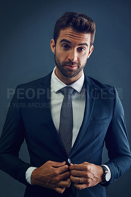 Buy stock photo Studio portrait of a handsome young businessman posing against a dark background