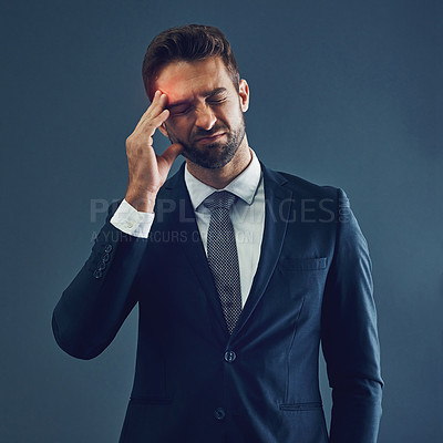 Buy stock photo Studio shot of a handsome young businessman suffering with a headache against a dark background