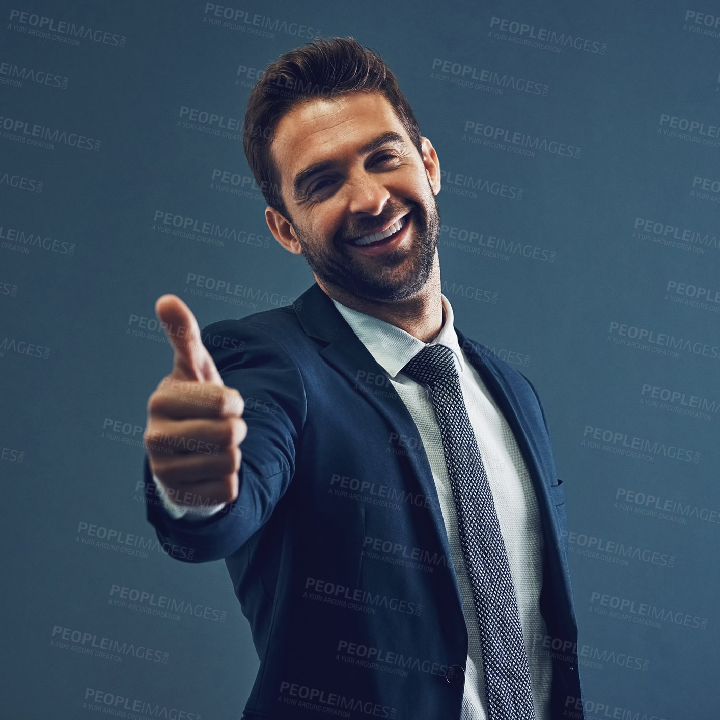 Buy stock photo Studio portrait of a handsome young businessman showing thumbs up against a dark background