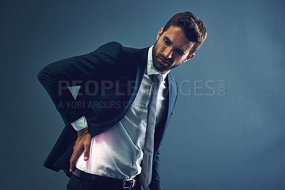 Buy stock photo Studio shot of a handsome young businessman posing against a dark blue background