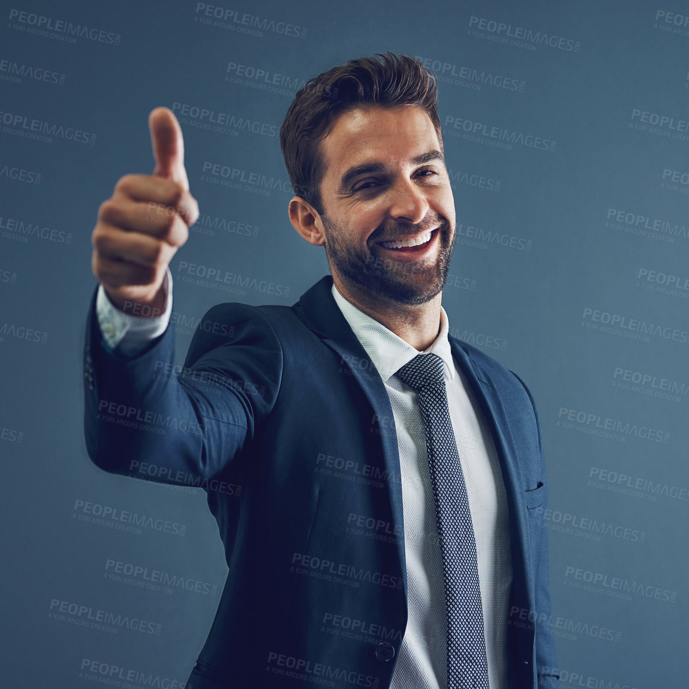 Buy stock photo Studio portrait of a handsome young businessman showing thumbs up against a dark background