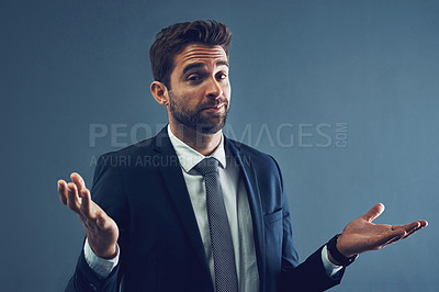 Buy stock photo Studio portrait of a handsome young businessman shrugging against a dark background