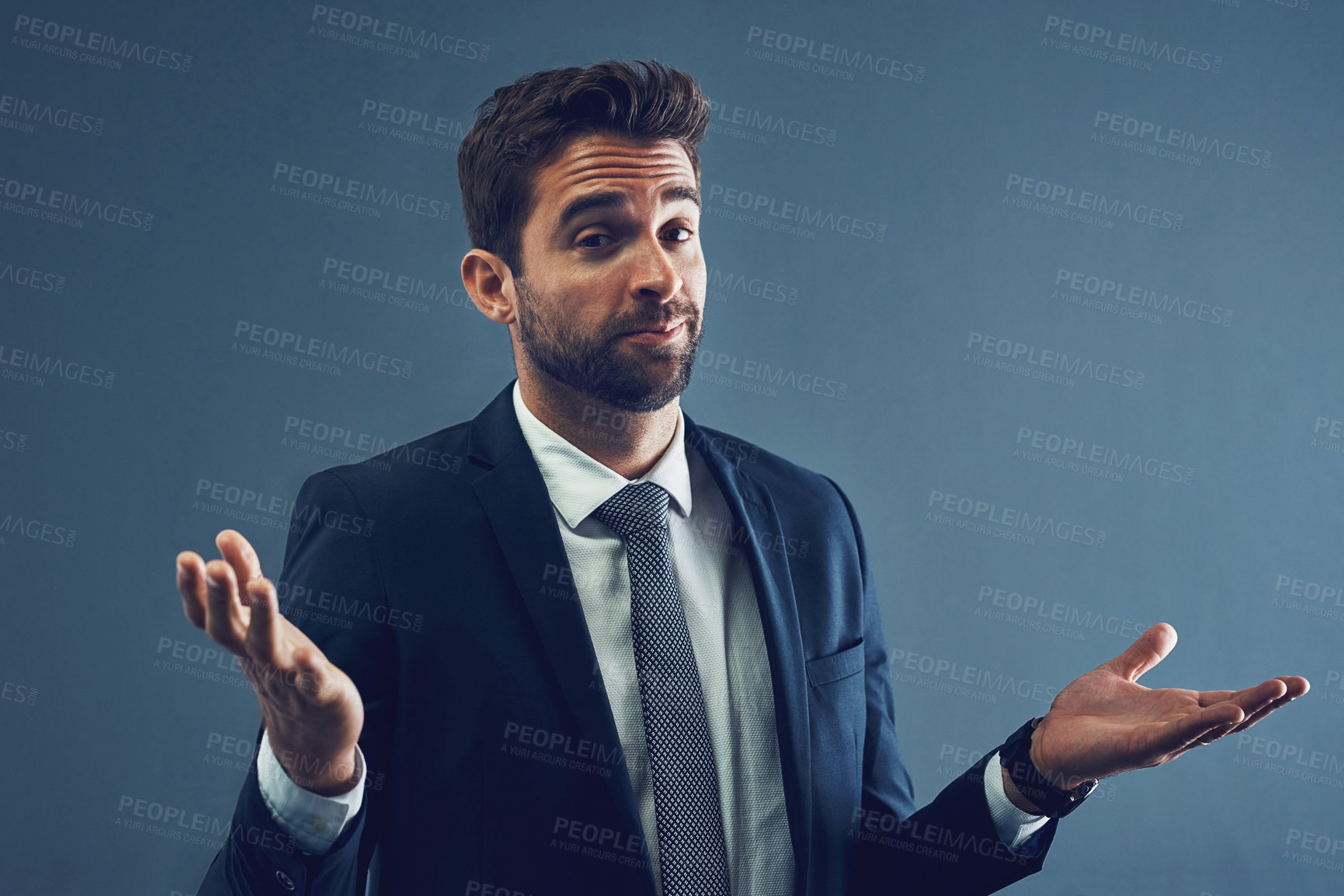 Buy stock photo Studio portrait of a handsome young businessman shrugging against a dark background