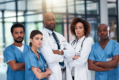 Buy stock photo Portrait of a confident group of doctors standing with their arms folded inside of a hospital during the day