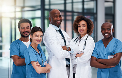 Buy stock photo Portrait of a cheerful group of doctors standing with their arms folded inside of a hospital during the day