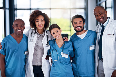 Buy stock photo Portrait of a cheerful group of doctors standing with their arms around each other inside of a hospital during the day