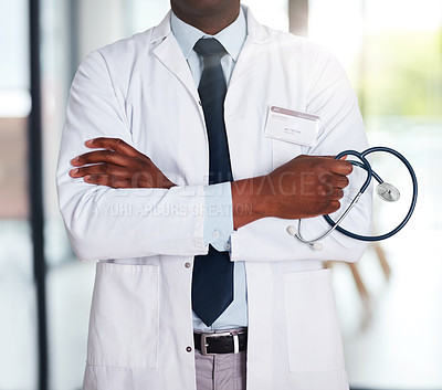 Buy stock photo Shot of an unrecognizable doctor standing with his arms folded while holding a stethoscope inside of a hospital
