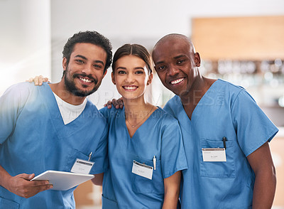Buy stock photo Portrait of a group of cheerful young doctors standing together with a digital tablet inside of a hospital