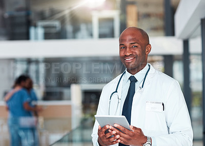 Buy stock photo Portrait of a cheerful young doctor browsing on a digital tablet while standing in a hospital during the day