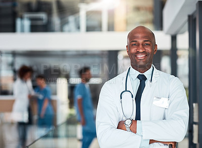 Buy stock photo Portrait of a cheerful young doctor standing with his arms folded inside of a hospital during the day