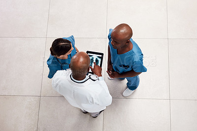 Buy stock photo High angle shot of two young doctors having a discussion over a digital tablet inside of a hospital