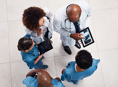 Buy stock photo High angle shot of a group of young doctors having a discussion over a digital tablet inside of a hospital