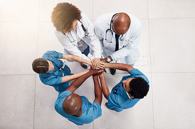 Buy stock photo High angle shot of a group of young doctors forming a huddle with their hands inside of a hospital during the day