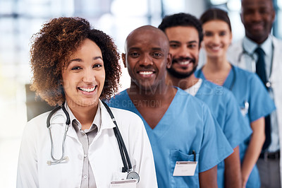 Buy stock photo Portrait of a cheerful young group of doctors standing behind each other inside of a hospital during the day