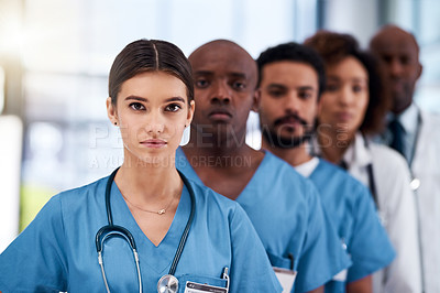 Buy stock photo Portrait of a confident young group of doctors standing behind each other inside of a hospital during the day