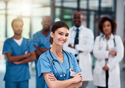 Buy stock photo Portrait of a cheerful young doctor standing with arms folded inside of a hospital during the day