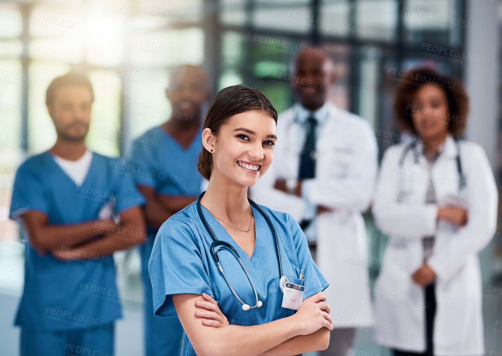 Buy stock photo Portrait of a cheerful young doctor standing with arms folded inside of a hospital during the day