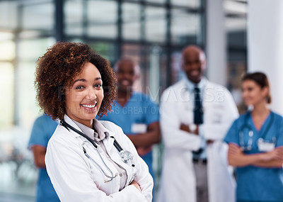 Buy stock photo Portrait of a cheerful young doctor standing with arms folded inside of a hospital during the day