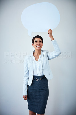 Buy stock photo Studio shot of an attractive corporate businesswoman holding up a speech bubble against a gray background