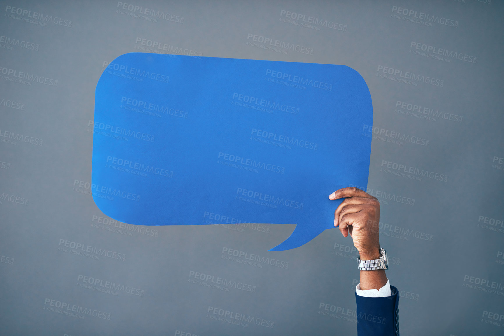 Buy stock photo Studio shot of an unrecognizable businessman holding up a blue speech bubble against a gray background