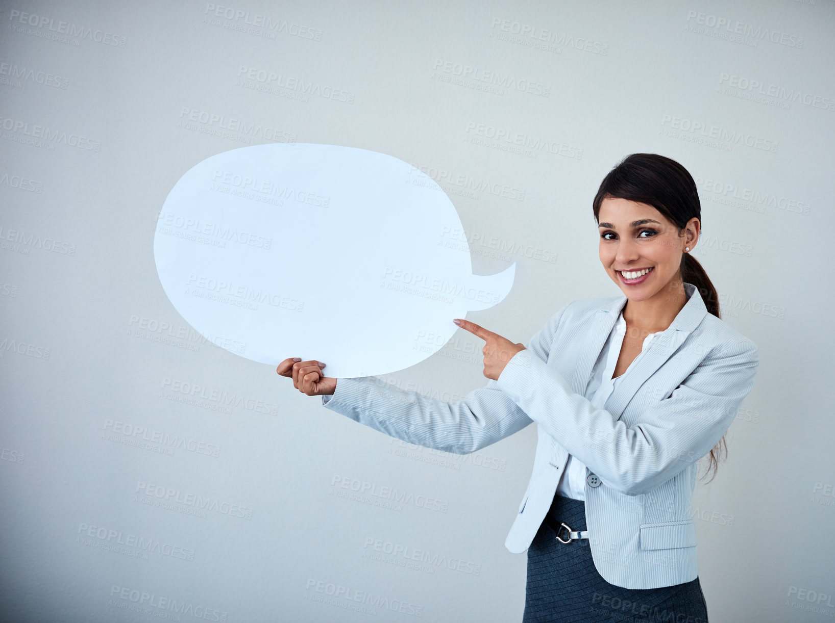 Buy stock photo Studio shot of an attractive corporate businesswoman holding up a speech bubble against a gray background