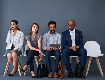 Buy stock photo Studio shot of a group of corporate businesspeople waiting in line against a gray background