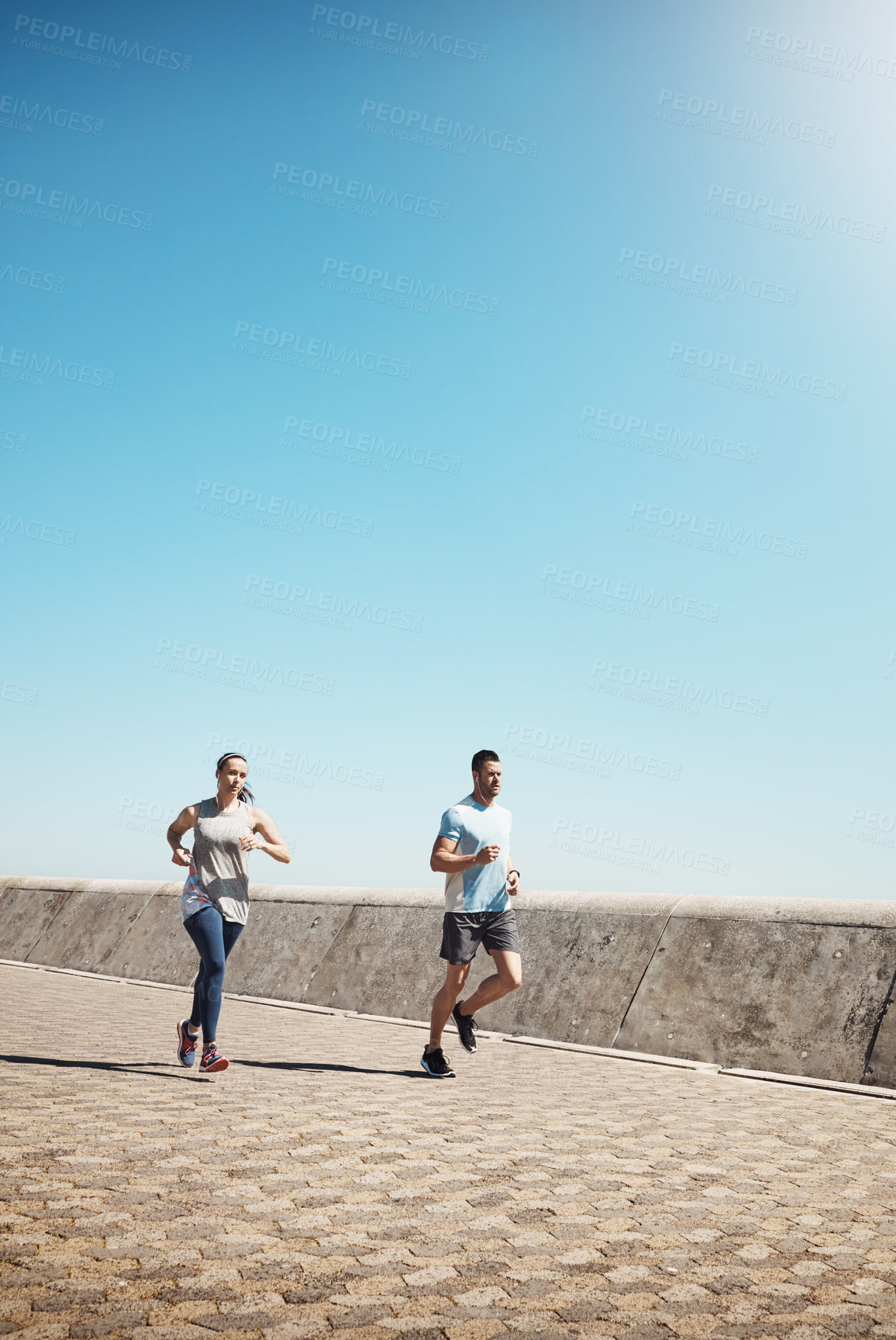 Buy stock photo Full length shot of a young couple out for a run on the promenade