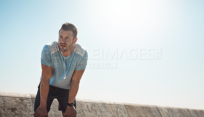 Buy stock photo Cropped shot of handsome young man looking tired during a run on the promenade
