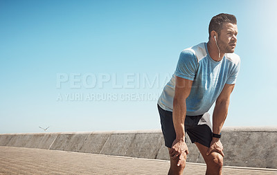 Buy stock photo Cropped shot of handsome young man looking tired during a run on the promenade