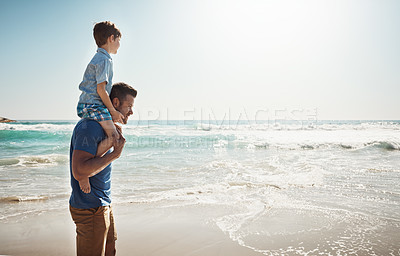 Buy stock photo Shot of a father carrying his little son on his shoulders at the beach