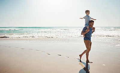 Buy stock photo Shot of a father carrying his little son on his shoulders at the beach